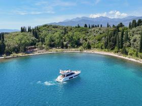 A stunning aerial view of a yacht cruising through crystal-clear waters, surrounded by lush greenery and mountains, perfect for showcasing luxury boating experiences.