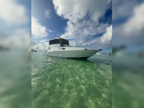 A sleek speedboat anchored in crystal-clear waters, showcasing its elegant design against a backdrop of blue skies and fluffy clouds.