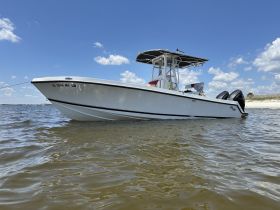 A sleek white boat anchored in calm waters, showcasing its elegant design against a clear blue sky — perfect for fishing or leisure outings.
