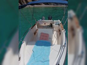 A cozy interior view of a boat's helm and seating area, featuring comfortable cushions and a serene turquoise backdrop — perfect for relaxing on the water.