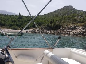 A serene view from the bow of a boat, showcasing the tranquil waters and rocky coastline, perfect for a day of exploration in nature.