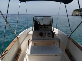 Interior view of a boat's helm and seating area, showcasing the console and steering wheel, perfect for navigating the open waters.