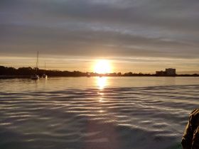 A serene sunset view featuring sailboats silhouetted against the vibrant sky, capturing the tranquility of a boating experience.