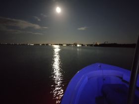A serene night view from the bow of a boat, illuminated by moonlight reflecting on the water — perfect for evening cruises and tranquil getaways.