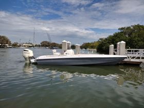 A sleek speedboat docked in calm waters, showcasing its modern design and fishing gear, perfect for a day on the water.