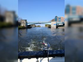 A scenic view of a waterway leading under a bridge, showcasing the tranquility of boating. Perfect for those looking to explore picturesque routes.