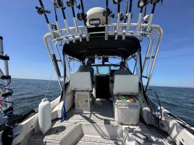 Inside view of a fishing boat's helm, showcasing the seating and equipment setup for an enjoyable day on the water.