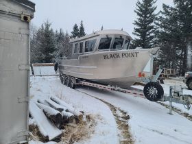 A silver boat named 'Black Point' is docked in a snowy landscape, showcasing its sturdy design and readiness for adventure.