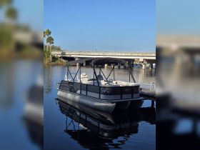 A sleek pontoon boat docked peacefully, reflecting on calm waters, ideal for leisurely outings and family fun.