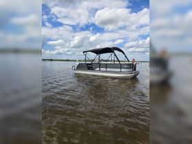 A pontoon boat glides through calm waters under a beautiful sky, with guests enjoying the ride — perfect for leisurely outings and family fun.