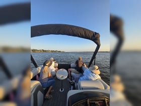 A group of friends enjoys a scenic boat ride, taking in the beautiful views of the water and shoreline — perfect for relaxing outings on the water.