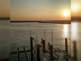A serene sunset view over a calm waterway, featuring a dock ready for boating adventures — perfect for capturing the tranquility of evening on the water.