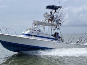 A fishing boat speeds through the water with crew members on board, showcasing the excitement of a day on the water.