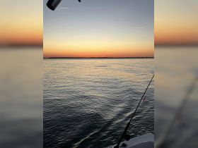 A serene sunset view over calm waters, captured from a boat, showcasing the tranquil beauty of evening on the water.