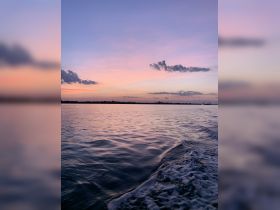 A stunning sunset over calm waters, capturing the serene beauty of the coastline — perfect for romantic evenings or peaceful boat rides.