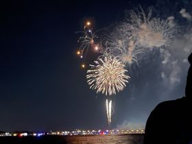 A stunning display of fireworks lights up the night sky over the waterfront, creating a festive atmosphere perfect for celebrations on the water.