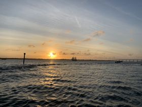 A stunning sunset over the harbor with a sailboat in the distance, creating a picturesque scene perfect for evening cruises.
