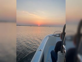 A serene sunset view from a boat, with a person enjoying the tranquil waters — perfect for capturing the beauty of evening cruises.