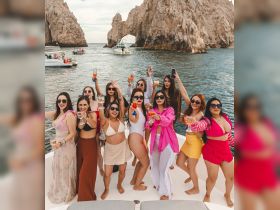 A lively group of friends celebrates aboard a boat, raising cocktails against a stunning coastal backdrop — perfect for bachelorette parties or group getaways.