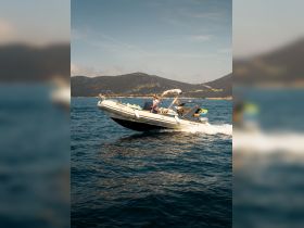 A speedboat performs an exciting maneuver on the water, showcasing the thrill of boating adventures against a stunning mountainous backdrop.