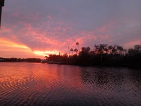 A stunning sunset casts vibrant colors over the water, creating a picturesque scene perfect for evening boat trips or romantic getaways.