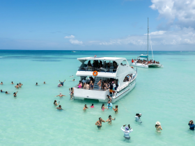 A lively scene at a sandbar with guests enjoying the water and partying on a boat, showcasing the ultimate tropical getaway experience.