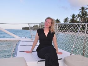 A woman relaxes on the deck of a catamaran, enjoying the serene ocean view — a perfect moment for leisure and tranquility on the water.