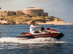 A thrilling ride on a jet ski, showcasing the excitement of water sports against a scenic backdrop of historic fortifications.