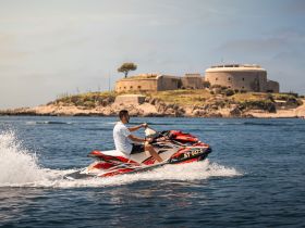 A rider enjoys a thrilling jet ski experience against the backdrop of a historic fortress, showcasing the excitement of water sports and scenic views.