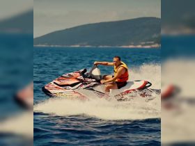 A man enjoys an exhilarating ride on a jet ski, creating splashes in the clear blue waters — perfect for adventure seekers looking for fun on the water.