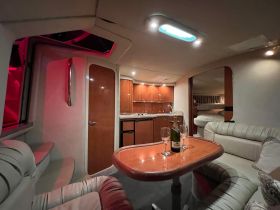 A cozy interior view of a boat cabin featuring elegant seating and a dining area, perfect for intimate gatherings or relaxing moments on the water.