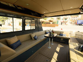 Interior view of a stylish boat cabin featuring comfortable seating and a dining area, perfect for relaxing while enjoying the scenic waterfront.