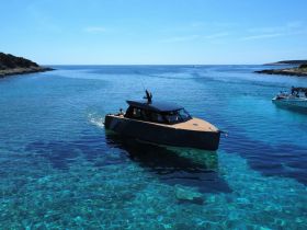 A sleek yacht navigates through crystal-clear waters, showcasing the beauty of a serene coastal landscape — perfect for luxury boating adventures.