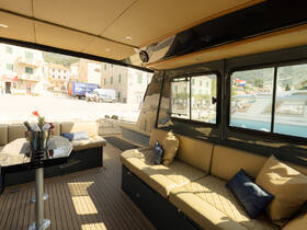 Interior view of a stylish boat lounge area featuring comfortable seating and a table, perfect for relaxing while enjoying the scenic waterfront.