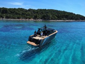A sleek boat navigates through crystal-clear waters with a group of people onboard, showcasing the perfect setting for a day of adventure on the sea.