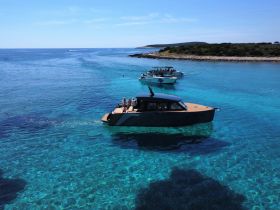 A stunning view of boats navigating through crystal-clear waters near an island, showcasing a perfect day for exploration and adventure on the water.