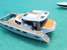Aerial view of a sleek catamaran cruising in clear turquoise waters, showcasing its spacious deck and modern design — perfect for luxury charters and island adventures.