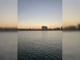 A serene view of a waterfront at dusk, showcasing buildings against a colorful sky. Ideal for capturing the tranquil essence of evening by the water.