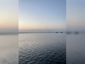 A serene view of calm waters at dusk, capturing the tranquil ambiance of the evening sky.