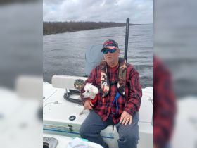 A man enjoys a day on the water with his small dog, showcasing a relaxing fishing experience on the boat.