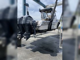 A Grady-White boat is lifted by a travel lift, showcasing its sleek design and powerful Yamaha engines — perfect for fishing or leisure on the water.