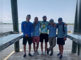 A group of friends poses together on a dock, ready for a day of fishing and adventure on the water.
