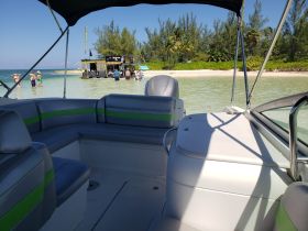 Guests enjoy a sunny day at the beach, swimming near a floating bar while relaxing on a pontoon boat — a perfect setting for fun in the sun.