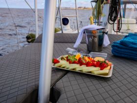 A beautifully arranged fruit platter and champagne await on the deck of a boat, perfect for a relaxing day on the water.