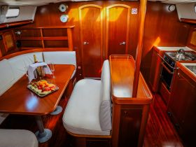 A cozy interior view of a boat's cabin featuring a dining area with fresh fruit and champagne, perfect for intimate gatherings or relaxing meals on the water.