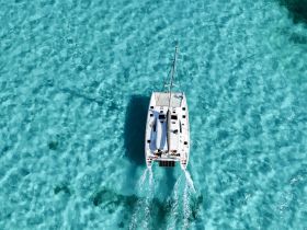 A stunning aerial view of a catamaran gliding through crystal-clear turquoise waters, perfect for showcasing the beauty of sailing adventures.