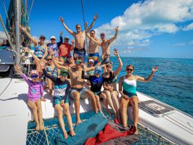 A lively group of friends and family celebrates aboard a sailboat, enjoying the sun and sea — perfect for memorable sailing adventures.