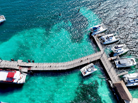 Aerial view of a vibrant dock with multiple boats anchored in stunning turquoise waters, showcasing a perfect spot for boating adventures.