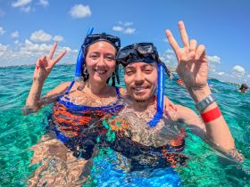 A happy couple enjoys snorkeling in crystal-clear waters, capturing a fun moment while exploring the underwater world.