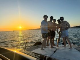 A group of friends enjoys a sunset celebration on a boat, capturing the perfect moment of camaraderie and fun on the water.